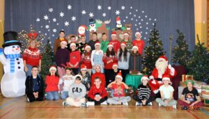 Uczniowie klasy 5a z Panią Ewą Kamińską i Mikołajem na tle zimowej dekoracji