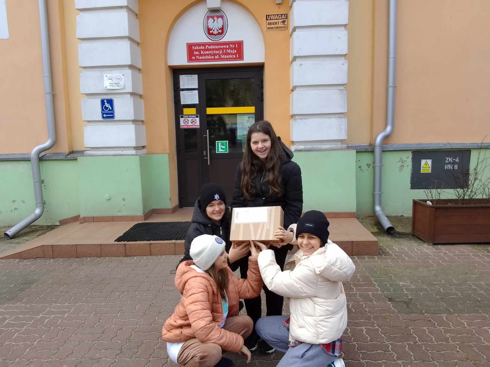 Karolina, Nikola, Eliza i Małgosia przed szkołą z paczką zapakowanych groszy